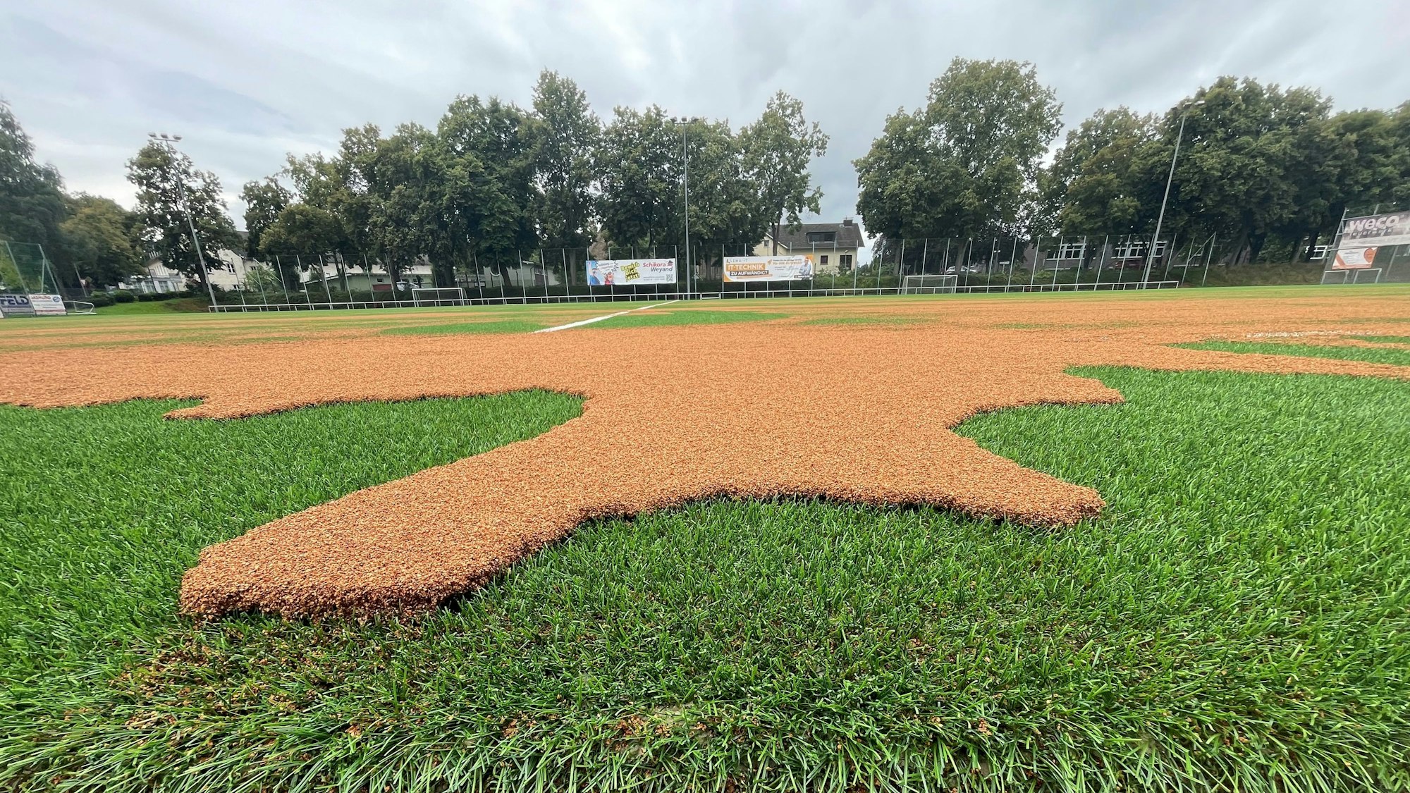 Auf dem Eitorfer Kunstrasenplatz haben sich große hellbraune Flecken gebildet. Es handelt sich um das vom Starkregen aufgeschwemmte Korkgranulat.