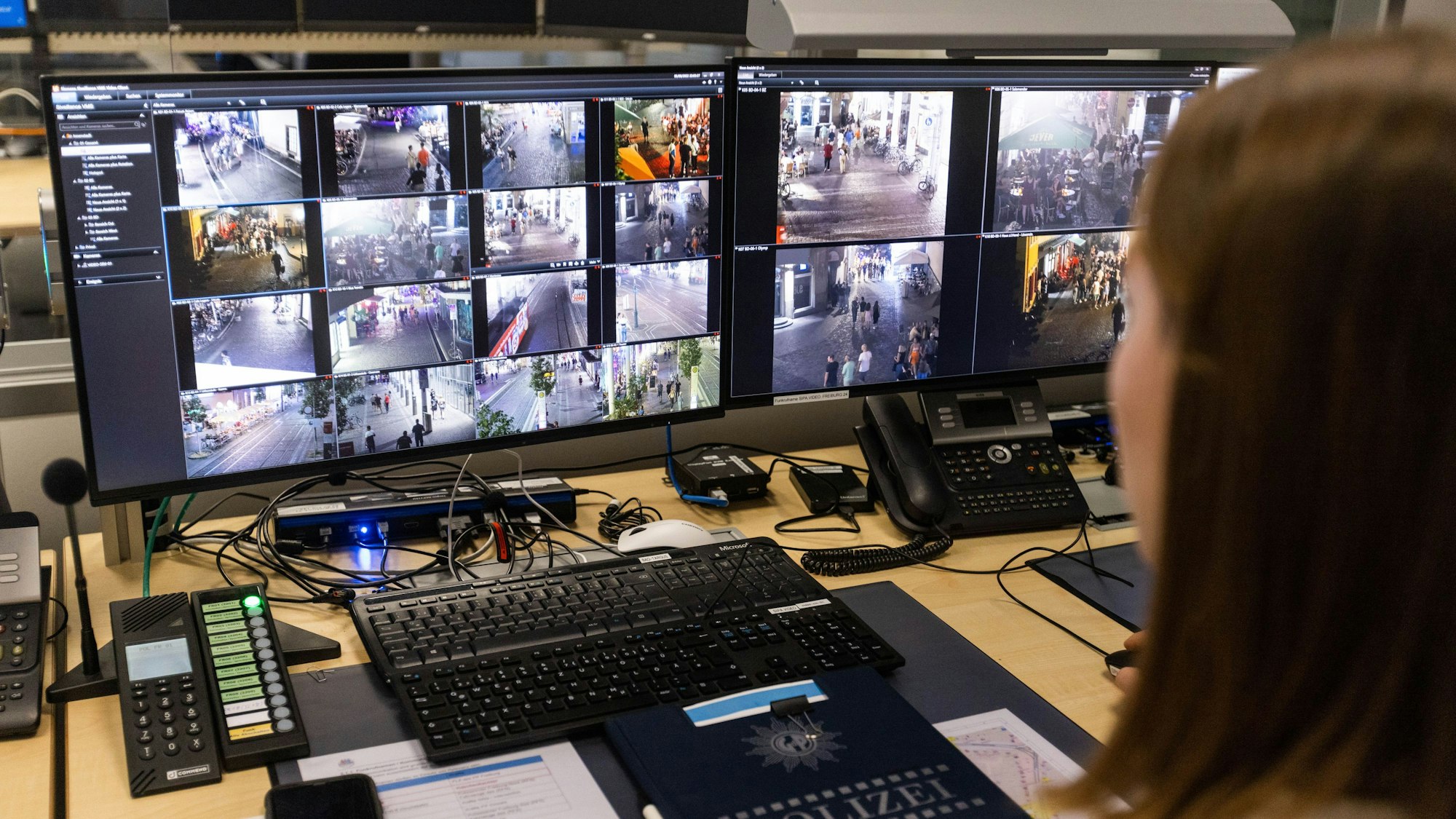 Ein Polizeibeamter sitzt vor Monitoren mit dem Livebild mehrerer Überwachungskameras.