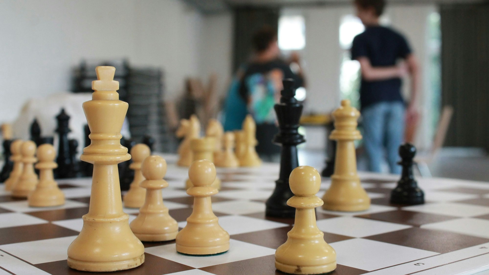 Ein Schachbrett, im Hintergrund Jugendliche