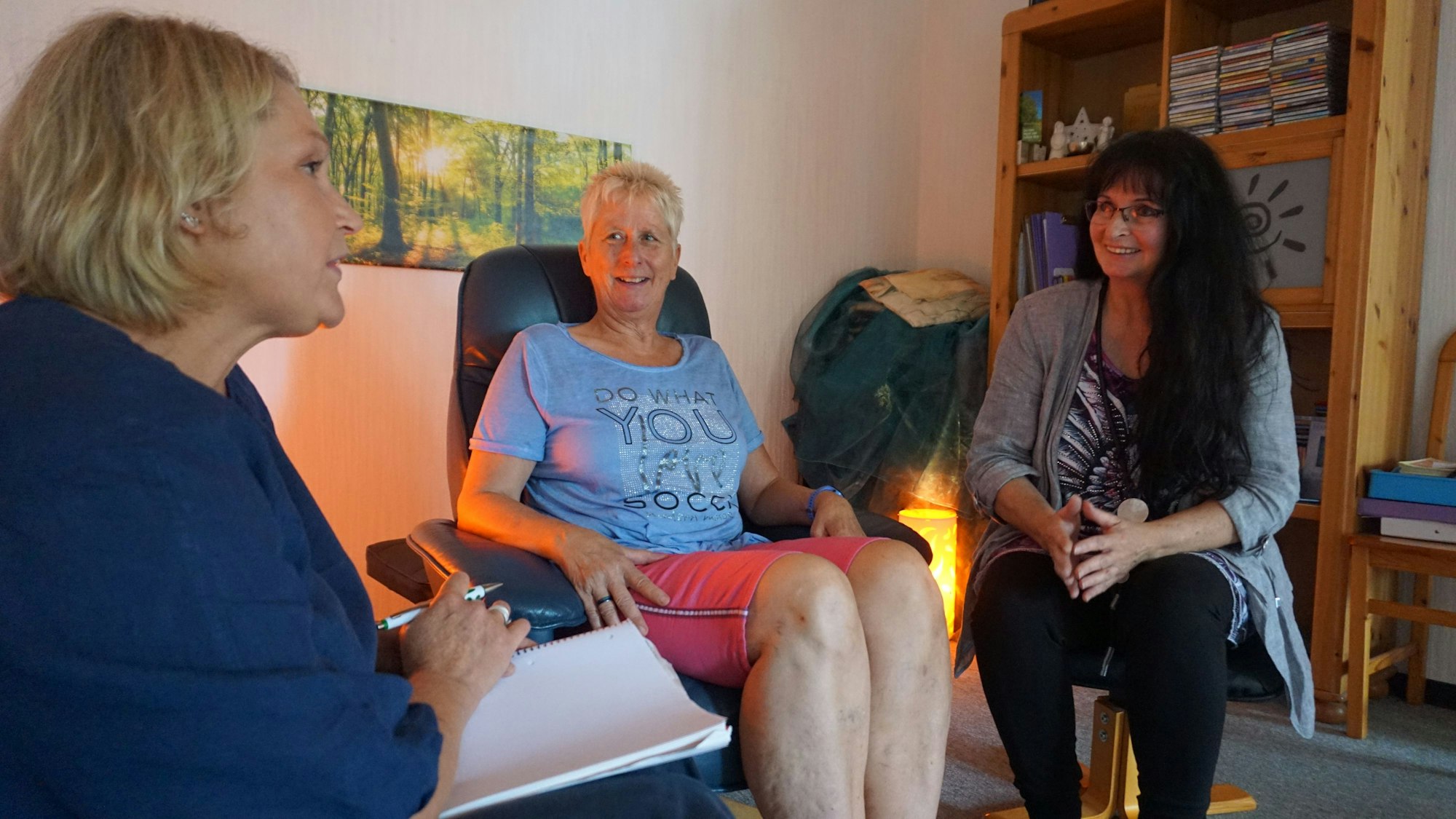 Nicole Giefer von der Selbsthilfe-Kontaktstelle, Patientin Manuela und Therapeutin Doris Linden-Schulz sitzen in den Therapieräumlichkeiten von Doris Linden-Schulz.