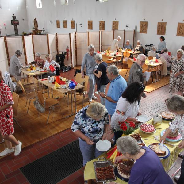 Gäste bedienen sich an einem Kuchenbuffet in einer Kirche.
