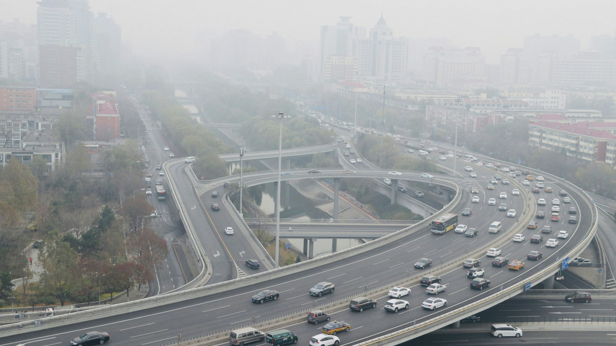 China, Peking: Autos fahren auf einer Straße, während starker Smog über der Stadt hängt.