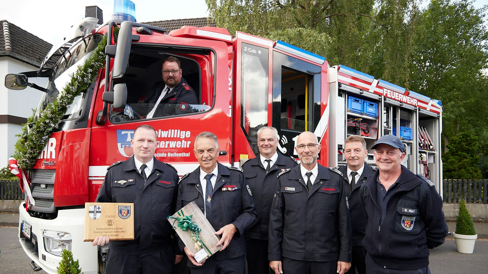 Sechs Männer stehen vor einem neuen und geschmückten Feuerwehrfahrzeug: Offiziell übergeben und eingesegnet ist das LF 10 der Löschgruppe Reifferscheid: Roland Mießen (v.l.), Rudolf Westerburg, Marcus Jenniches, Daniel Pützer, Arndt Haas und Bernd May. Am Steuer sitzt Maschinist Andreas Krahe.