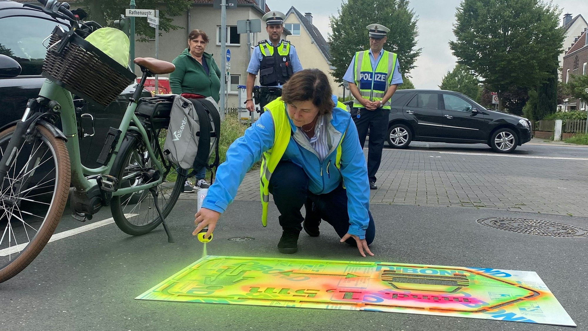 Christiane Jäger, Fachbereichsleiterin für Mobilität und Klimaschutz, sprayt einen signalfarbenen Hinweis auf die Straße.
