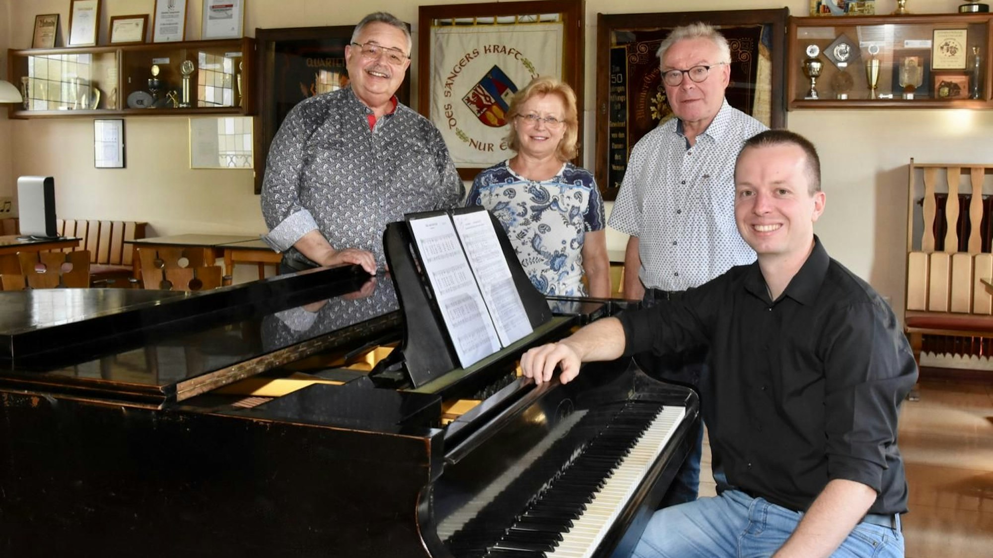 Ein junger Mann in schwarzem Hemd sitzt an einem Flügel, an der Seite stehen zwei Männer und eine FrauEitorfer Gesangverein: v.l.: Winfried Quodbach, Rosa Bader, Günter Marx, Karsten Rentzsch.