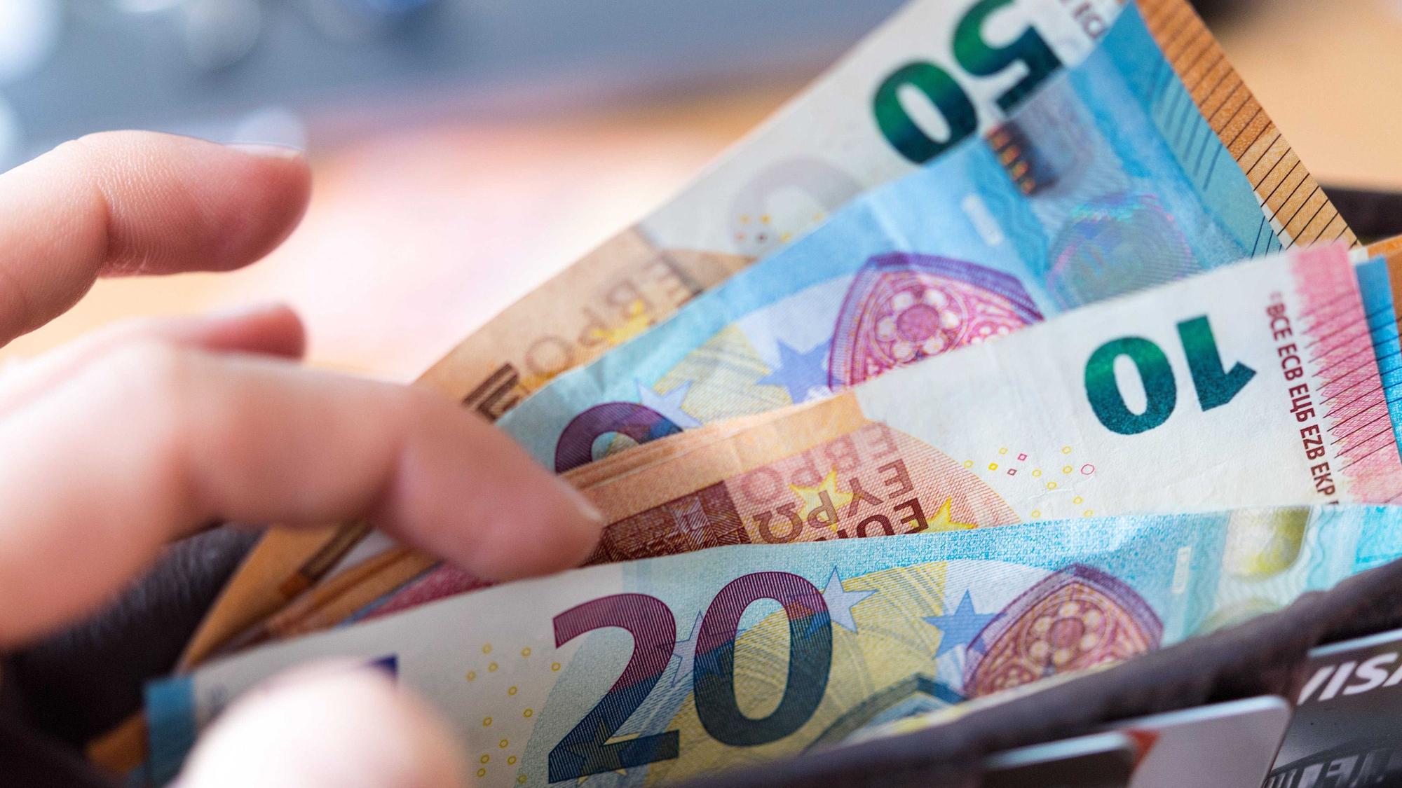 Eine Frau hält eine Geldbörse mit Banknoten in der Hand.