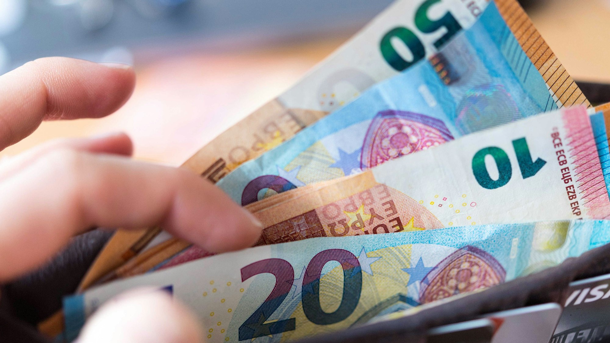 Eine Frau hält eine Geldbörse mit Banknoten in der Hand.