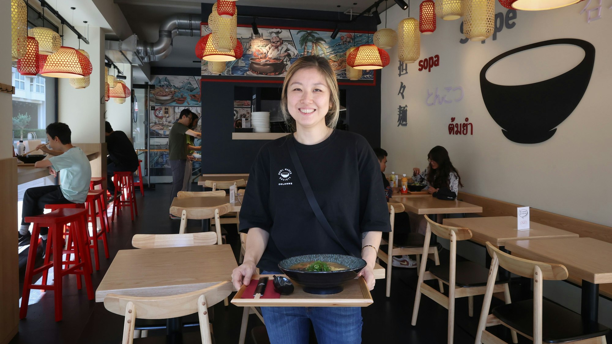 Li Ma steht mit einem Tablett in ihrem neuen Restaurant.