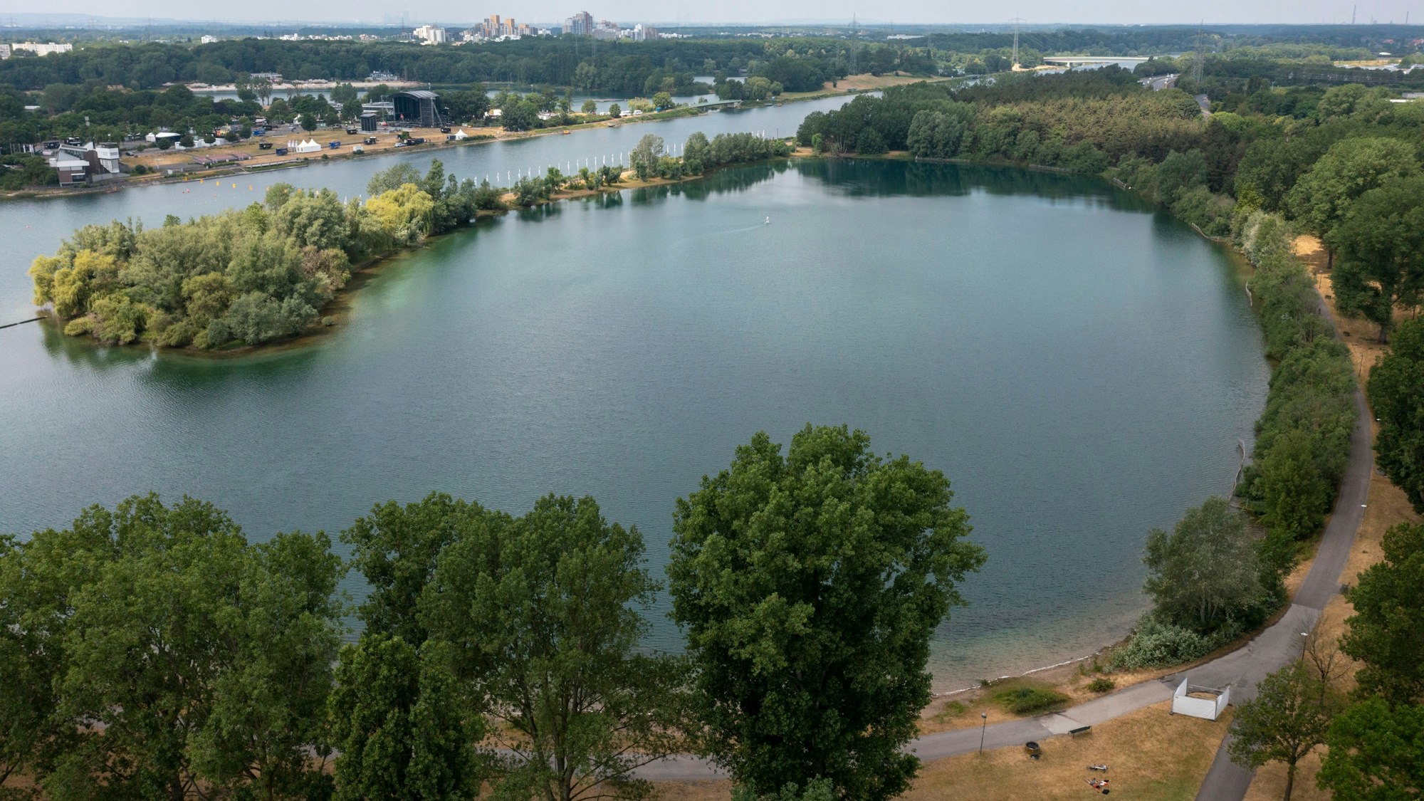 Blick auf einen nahezu runden Teilsee des Fühlinger Sees. Drumherum stehen Bäume, das Wasser ist grün-bläulich.