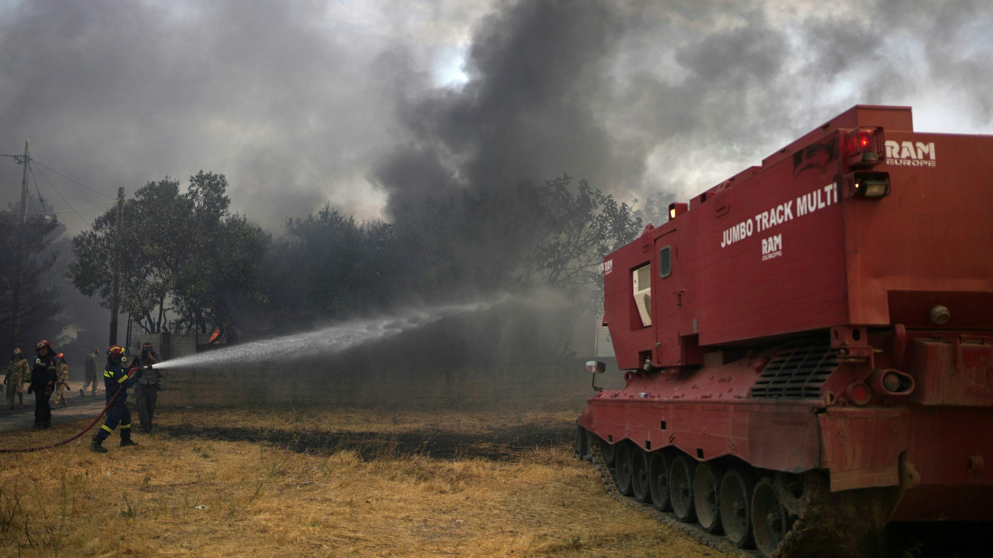 Feuerwehrleute versuchen mit Hilfe eines umgebauten Leopard-Panzers den Waldbrand neben dem christlich-orthodoxen Kloster Agia Paraskevi unter Kontrolle zu bringen. Das Spezialfahrzeug verfügt über eine  Kapazität für 15.000 Liter Löschwasser, einer Schaufel für unwegsames Gelände und einer Rettungskammer für zehn Menschen.