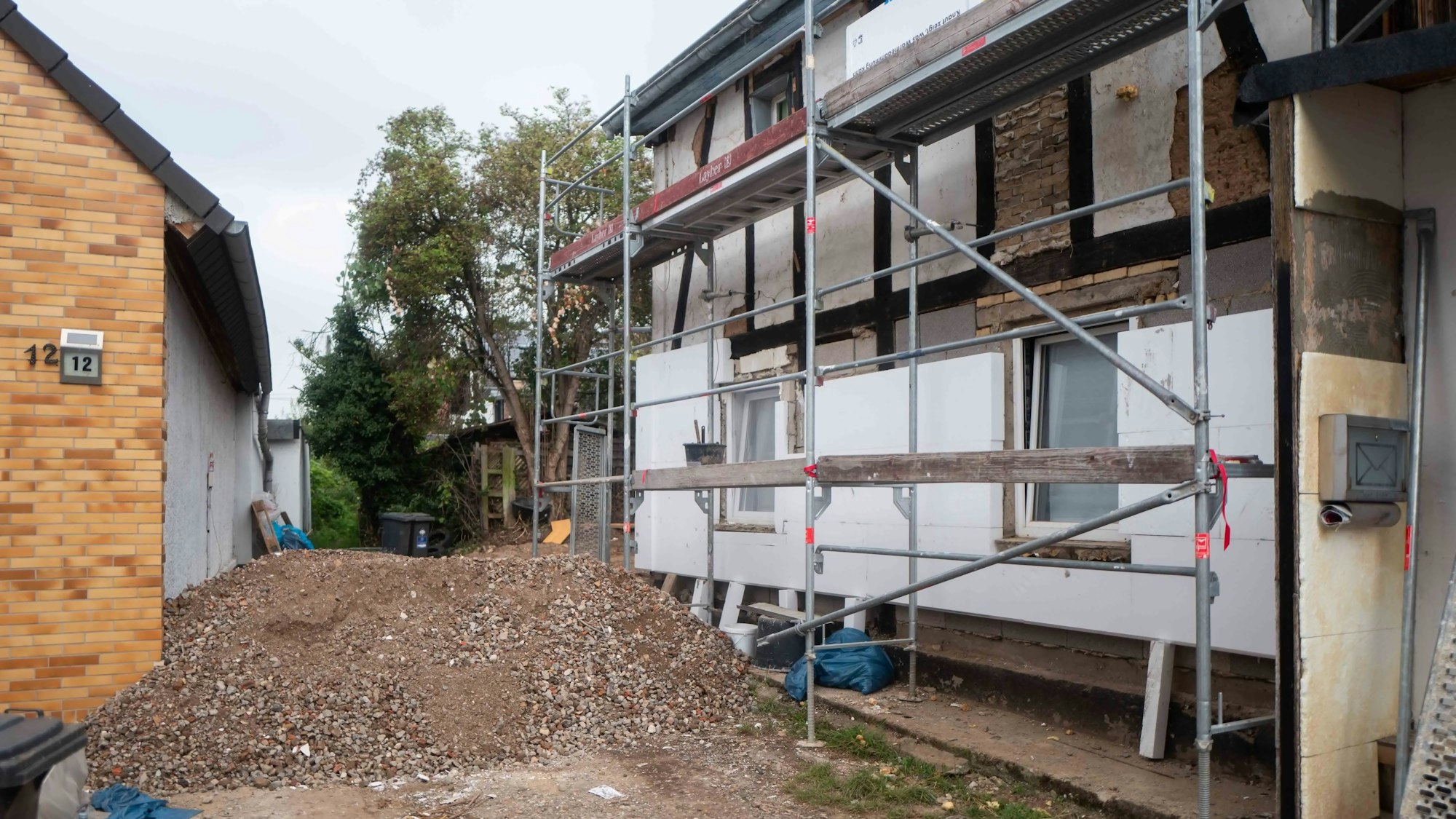Das Bild zeigt das Haus in Großbüllesheim. Zu erkennen ist ein großer Haufen aus Steinen und Erde. Zudem ist ein Gerüst aufgestellt worden.