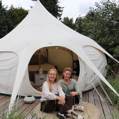 Die beiden Frauen sitzen vor dem Zelt.