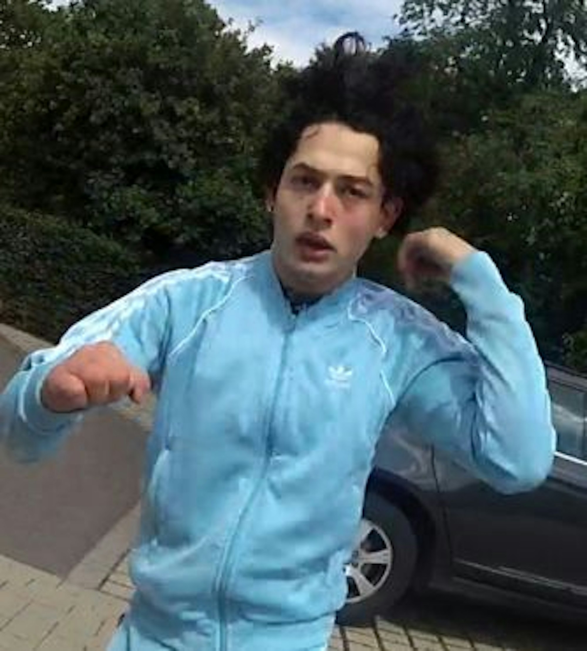 Foto einer Bodycam der Kölner Polizei. Ein Mann mit hellblauem Trainingsanzug guckt agressiv in die Kamera.