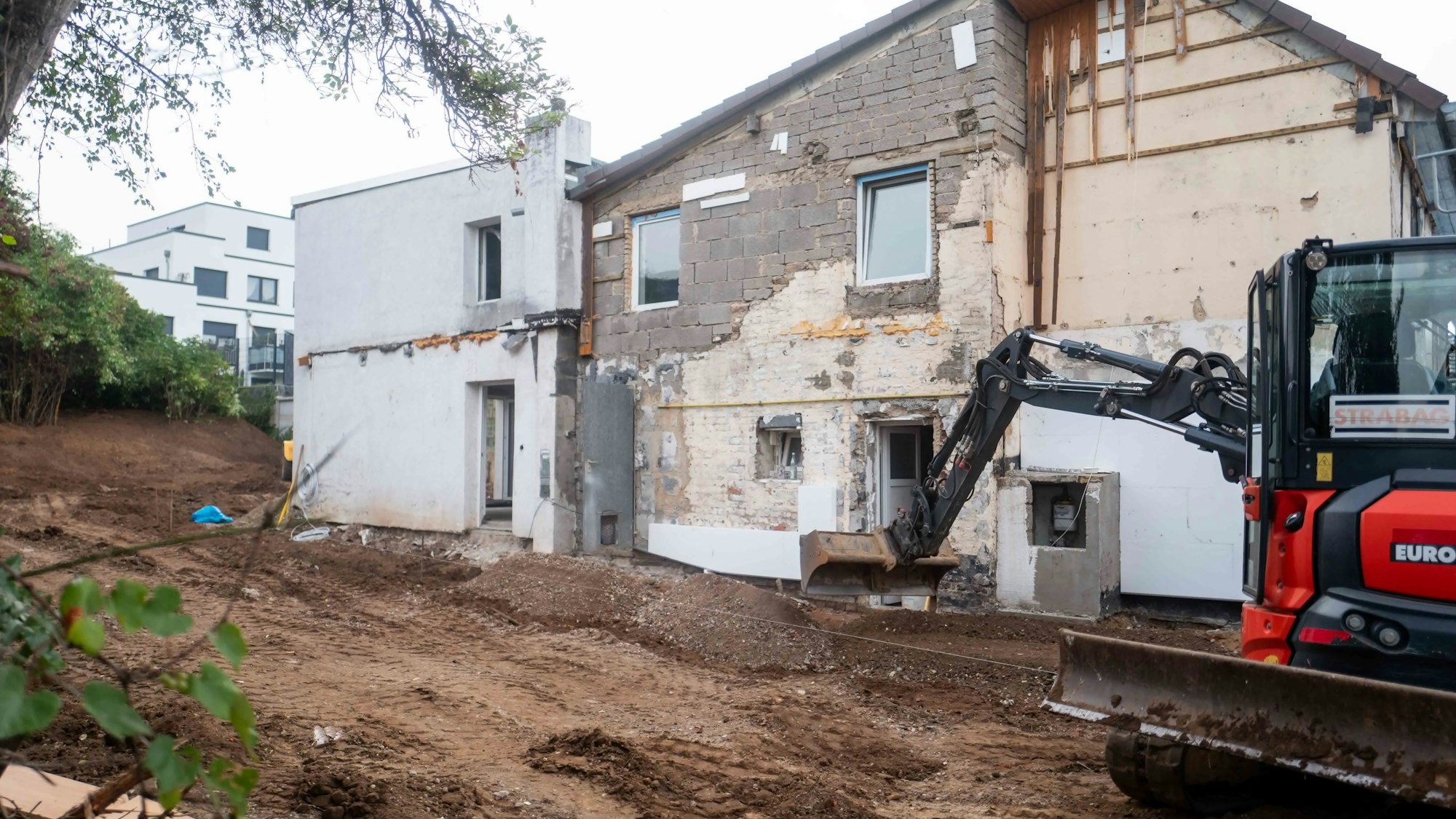 Das Bild zeigt einen Bagger, der den Außenbereich des Hauses in Großbüllesheim umgestaltet.