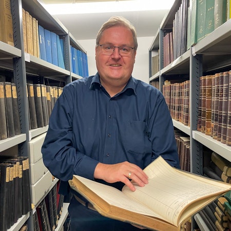 Norbert Bangert blättert im Archiv in einem Buch.