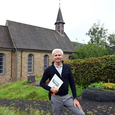 Der Makler Christoph Langer ist mit dem Verkauf der katholischen Kirche in der Morsbacher Ortschaft Ellingen beauftragt. Zum Grundstück gehört auch ein Teil des Friedhofs, auf dem der Reichshofer hier steht. In den Händen hält er das Exposé dieser ungewöhnlichen Immobilie.