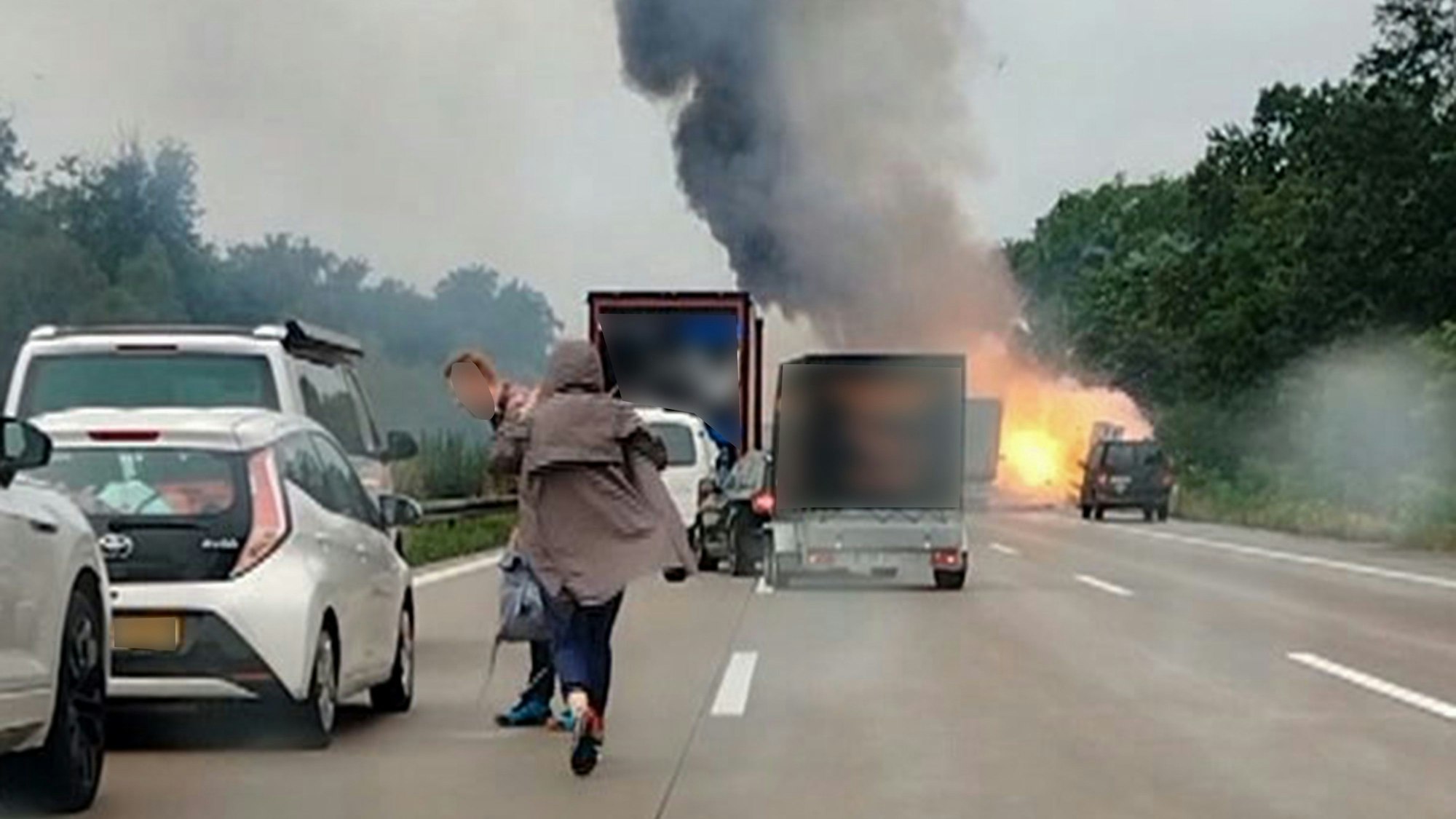 29.08.2023, Sachsen-Anhalt, Theeßen: Autofahrer verlassen ihre Fahrzeuge, während im Hintergrund ein LKW in Flammen. Auf einem Laster sind am Dienstag auf der Autobahn 2 zwischen Theeßen und Burg in Sachsen-Anhalt bei einem Auffahrunfall mehrere Gasflaschen explodiert. Beide Fahrtrichtungen waren auch am Nachmittag noch gesperrt. (Bestmögliche Bildqualität) Foto: -/TNN/dpa +++ dpa-Bildfunk +++