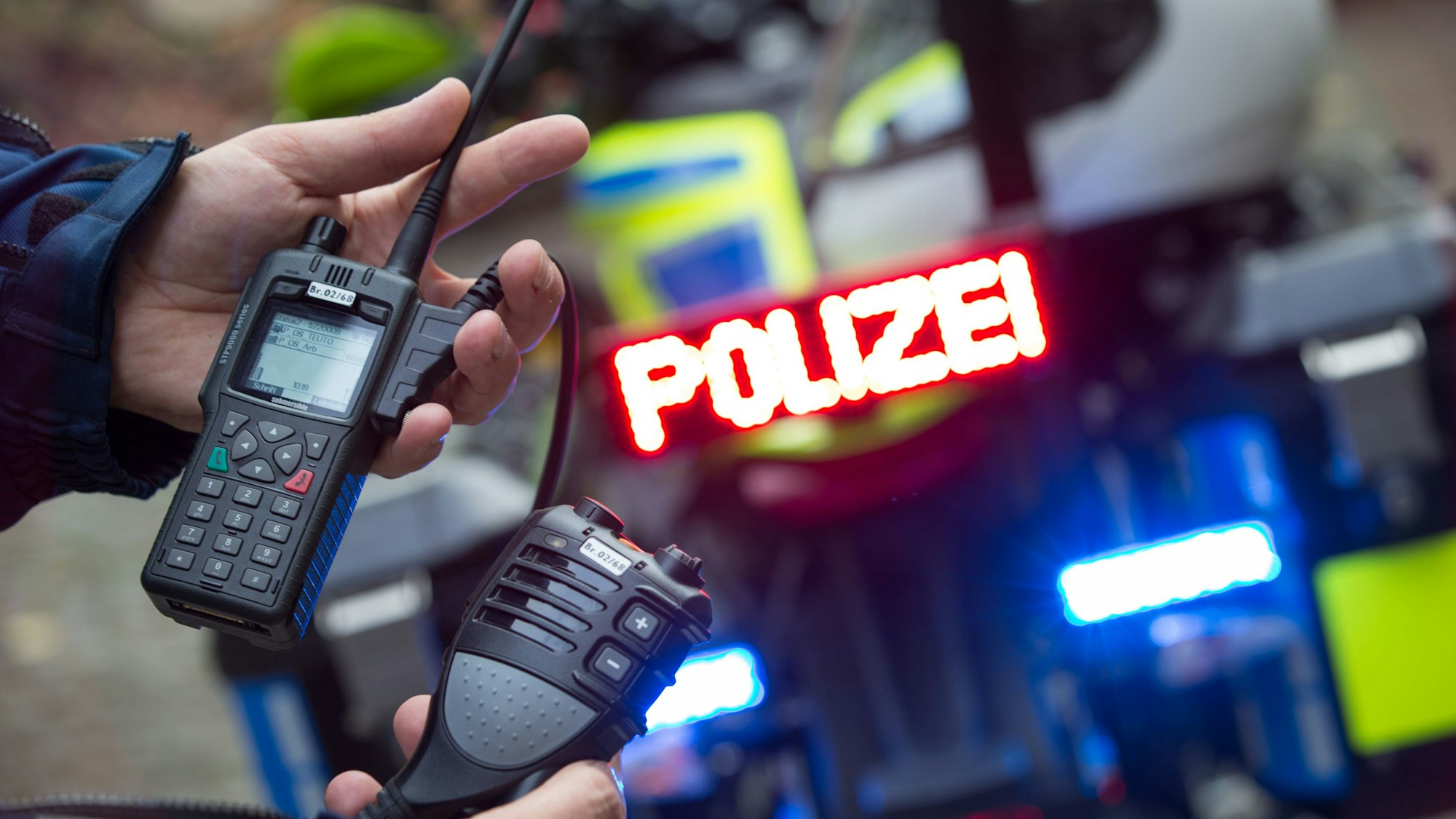 Ein Polizist hält ein neues kabelloses Bluetooth-Sprechfunkgerät in der Hand, das für den Einsatz auf einem Elektro-Polizeimotorrad konzipiert ist.