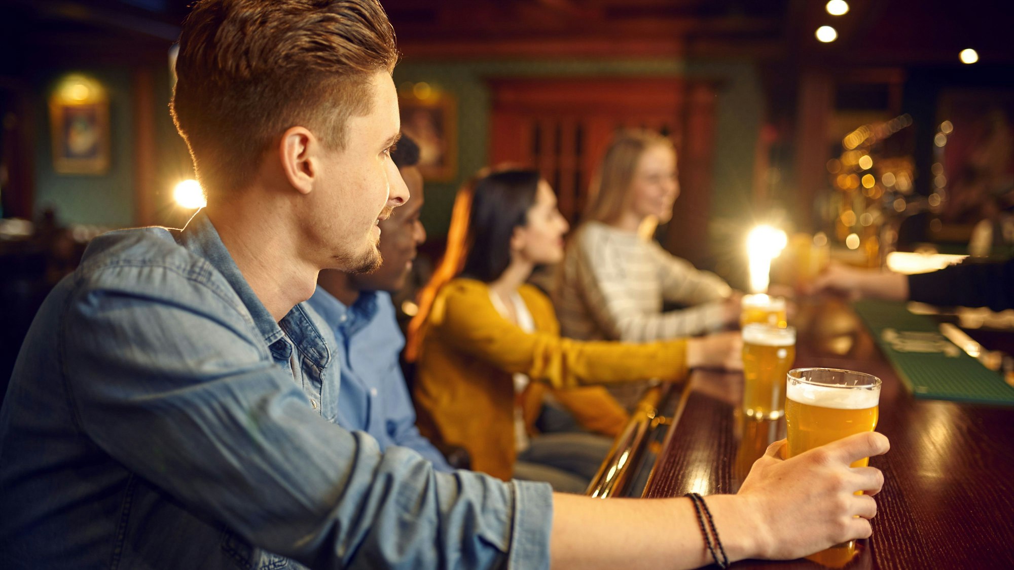 Junge Menschen sitzen in einer Bar und trinken Bier. (Symbolbild)