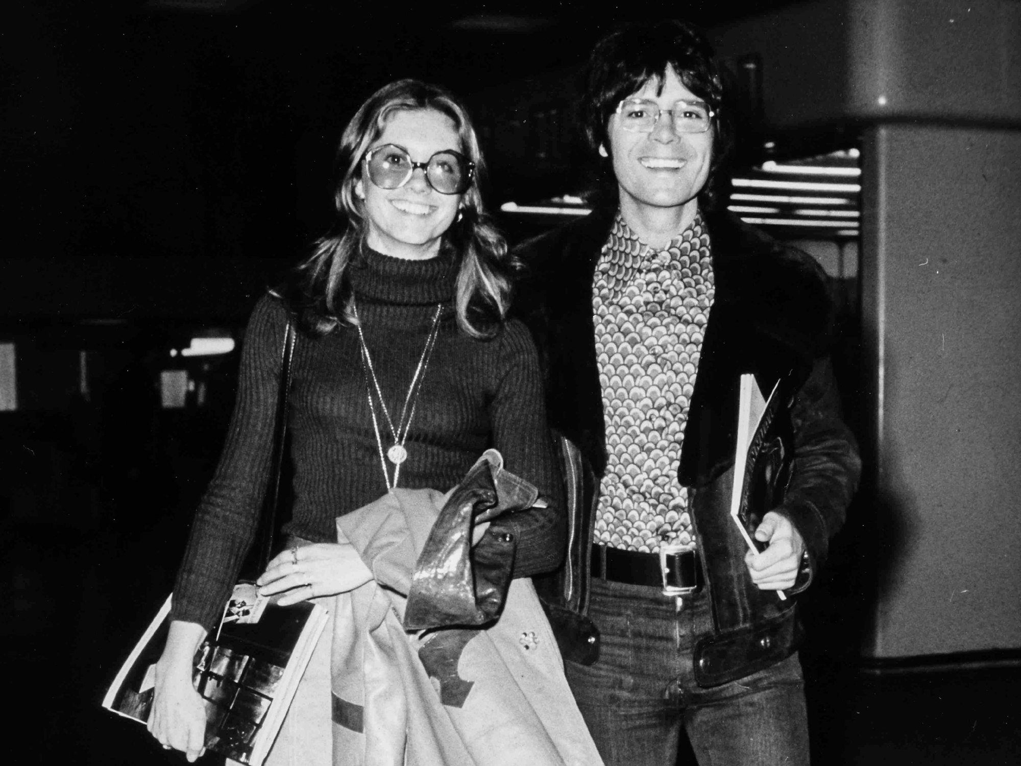 Olivia Newton-John und Cliff Richard gehen Arm in Arm.