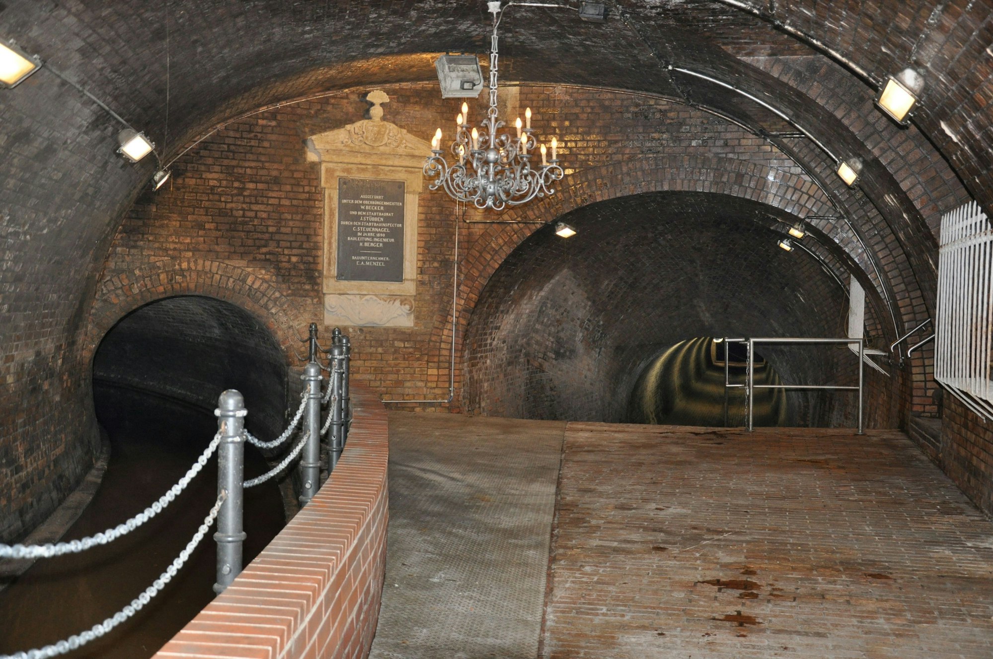 Die alte Kanalisation ist mit Backsteinen gebaut und hat einen rötlichen touch. Er Kronleuchter hängt von der Decke.
