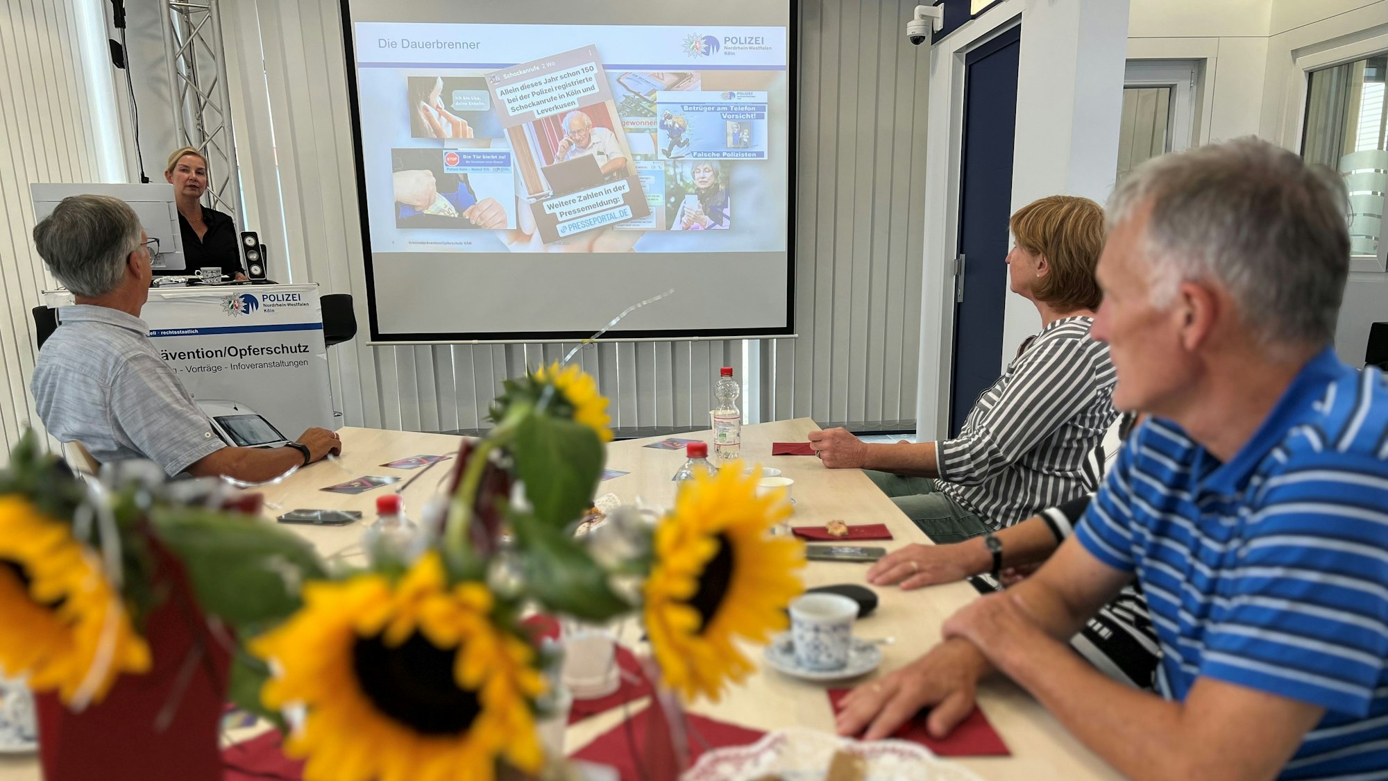 Im Polizeipräsidium in Kalk sitzen drei pensionierte Polizistinnen und Polizisten an einem Tisch und werden für ihre Präventionsarbeit geschult.