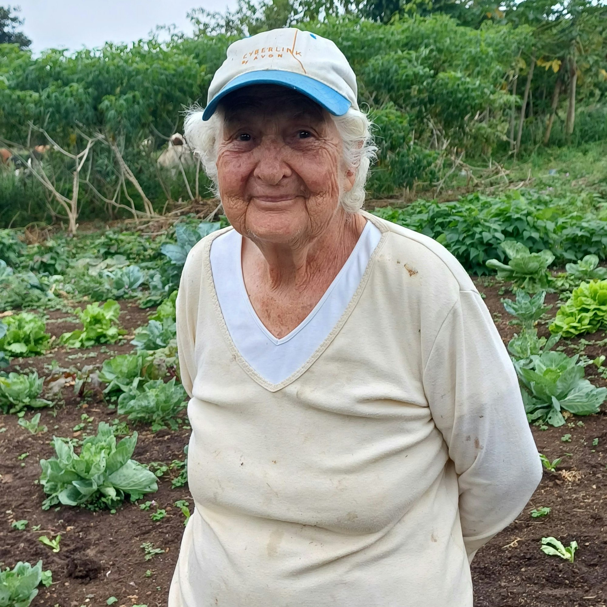 Ingeborg Wittmer in ihrem Garten, sie trägt eine Kappe und ein beiges Shirt