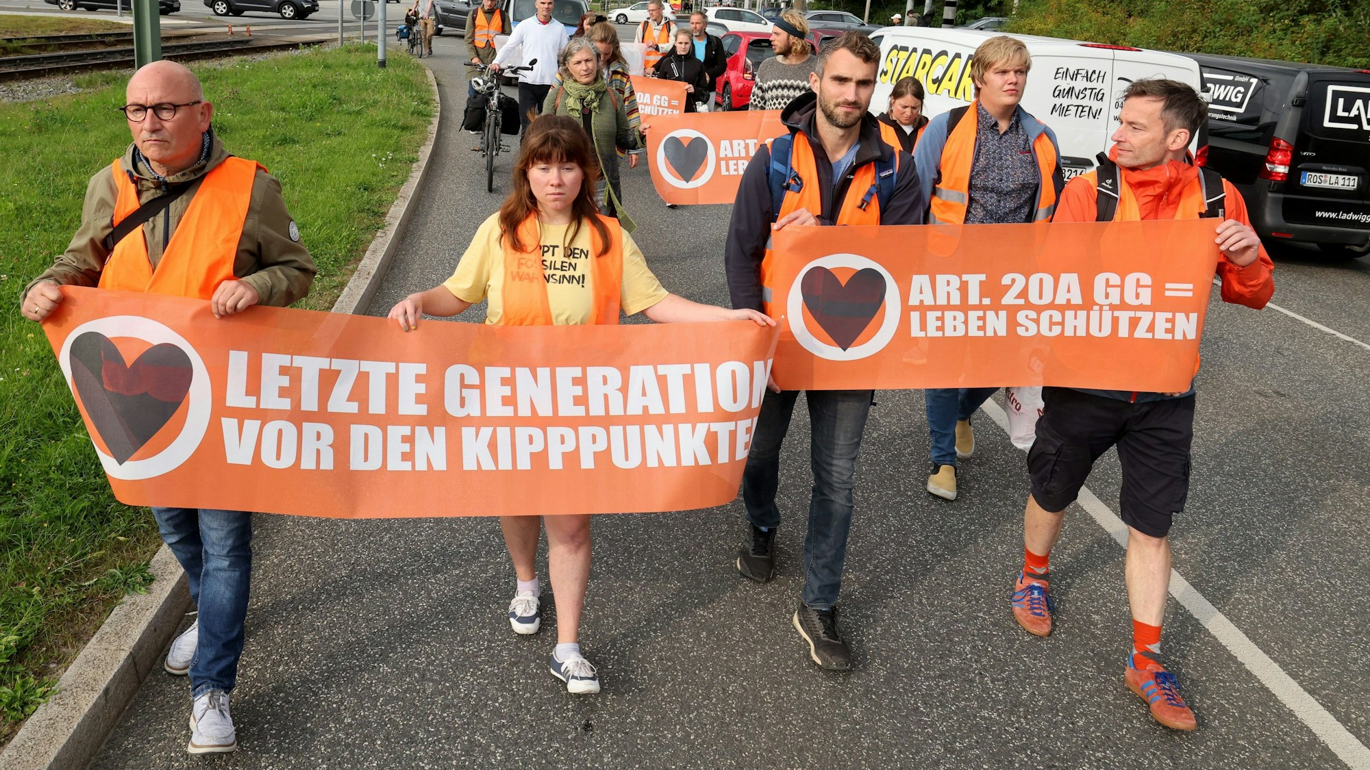 Klimaaktivisten der „Letzten Generation“ halten bei einem Protestmarsch Banner mit der Aufschrift „Vor den Kipppunkten“ und „Leben schützen“.