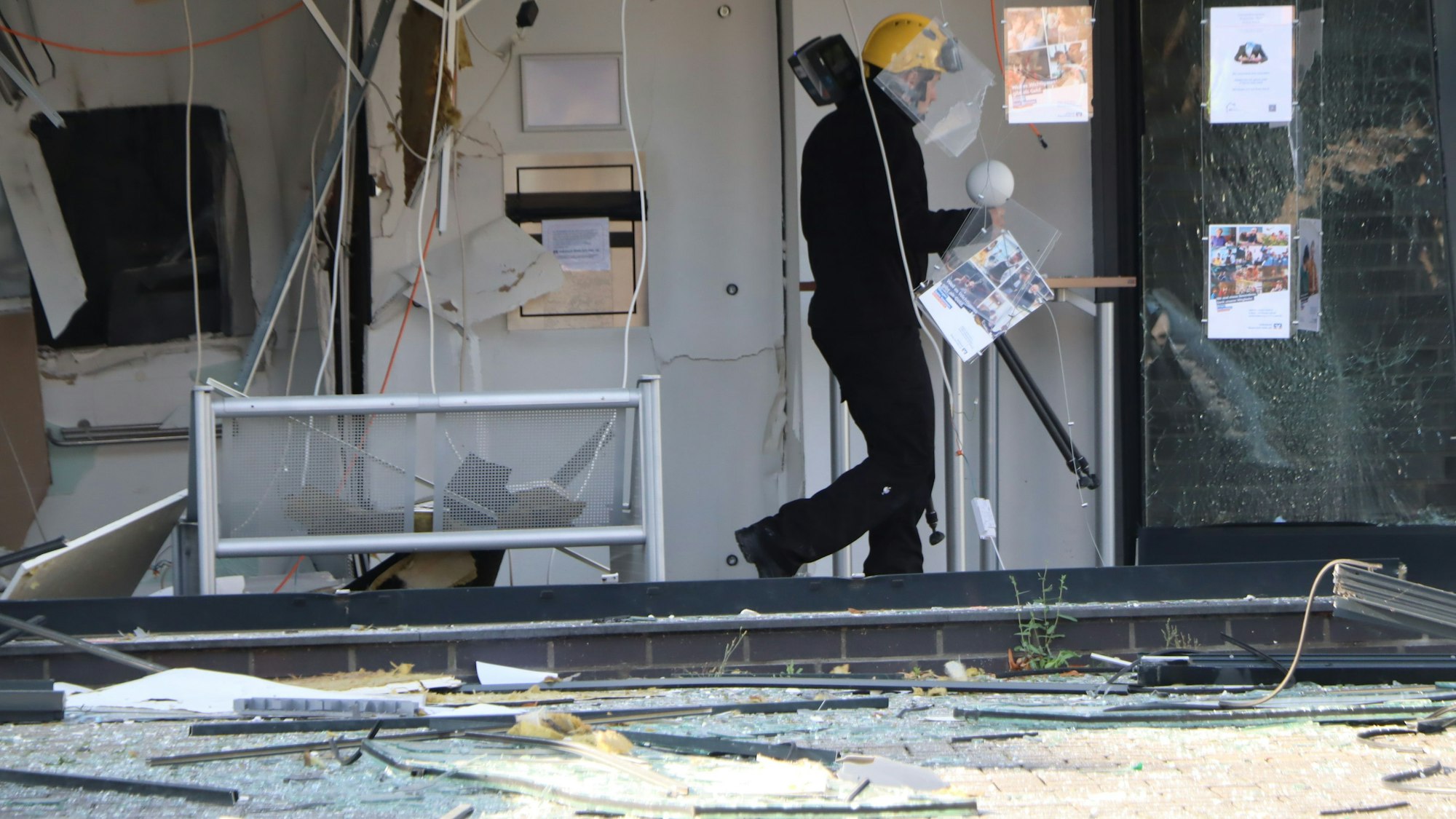 Auf dem Foto ist zu sehen, wie ein Mann spuren in der zerstörten Bankfiliale sichert.