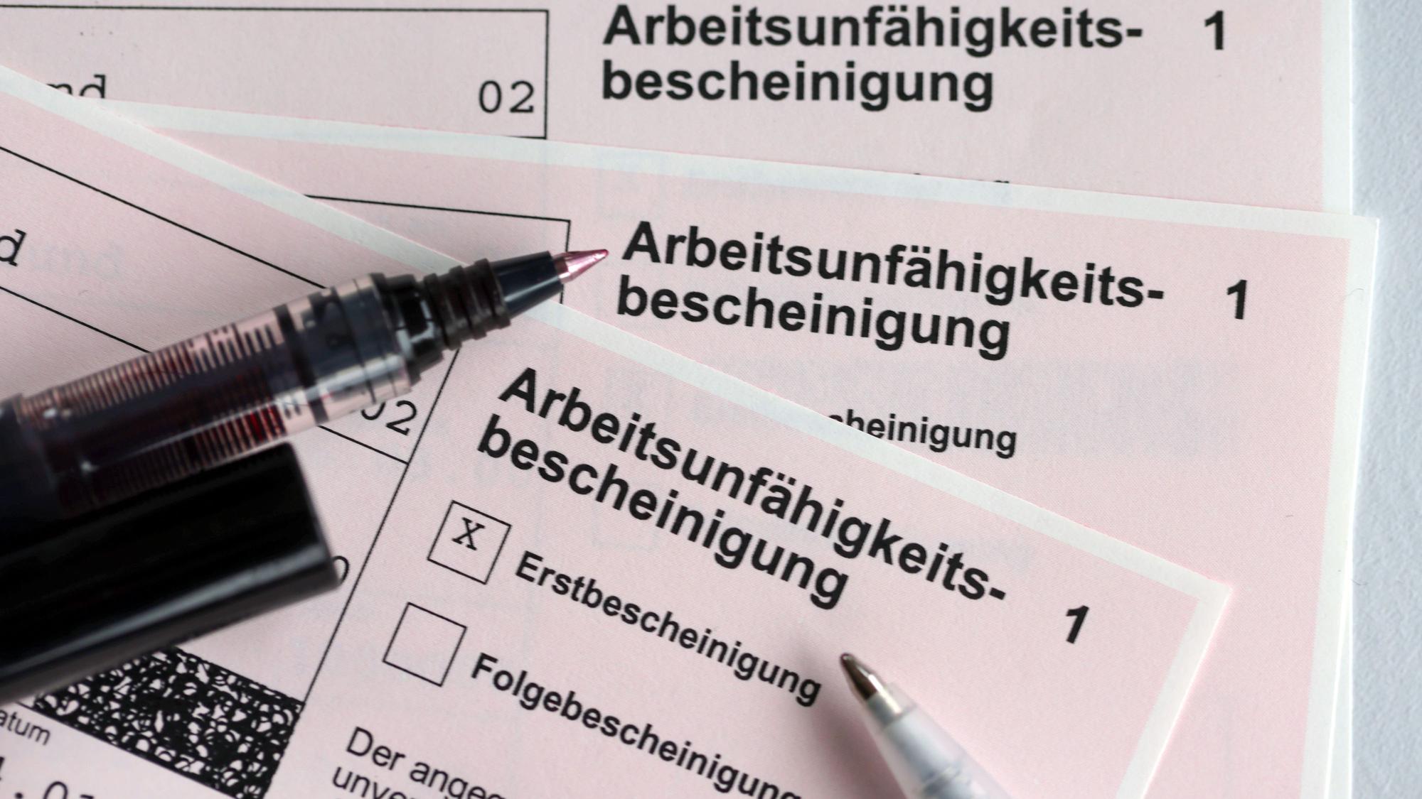 Ausschnitte von Arbeitsunfähigkeitsbescheinigungen und Stiften