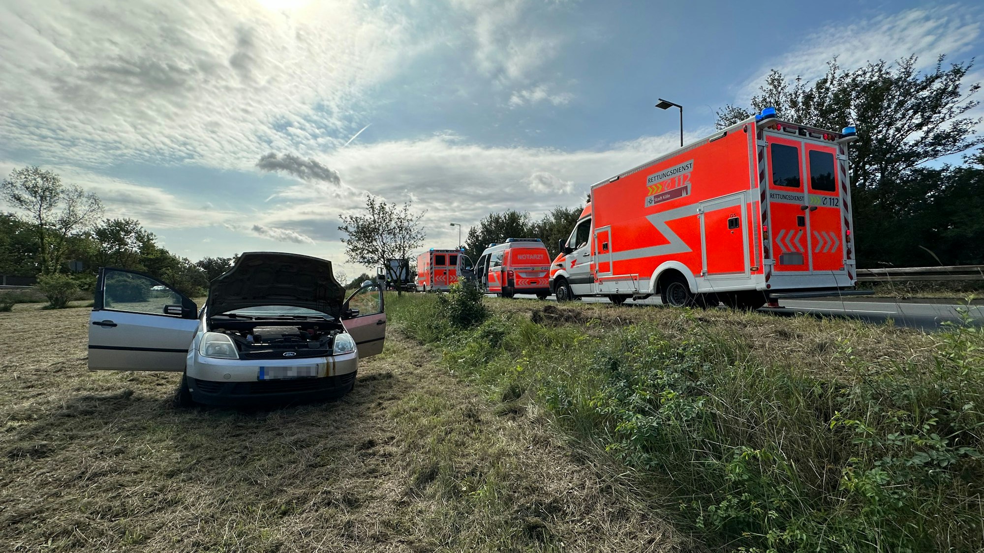 Ein Pkw steht nach einem Unfall mit einem Lkw am Donnerstag, 31. August 2023, am Niehler Ei in Köln neben der Straße. Am Straßenrand parken mehrere Rettungsfahrzeuge.