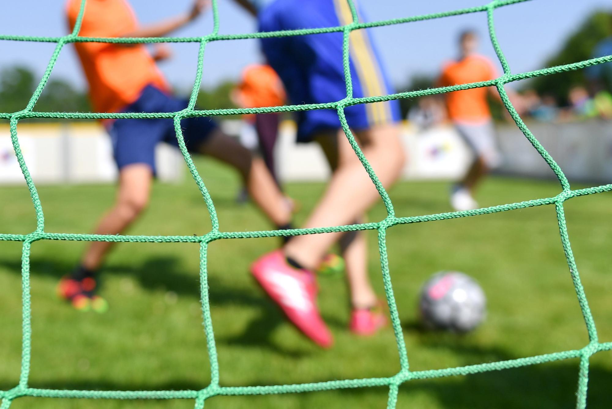Jugendliche spielen auf einem Sportplatz Fußball.