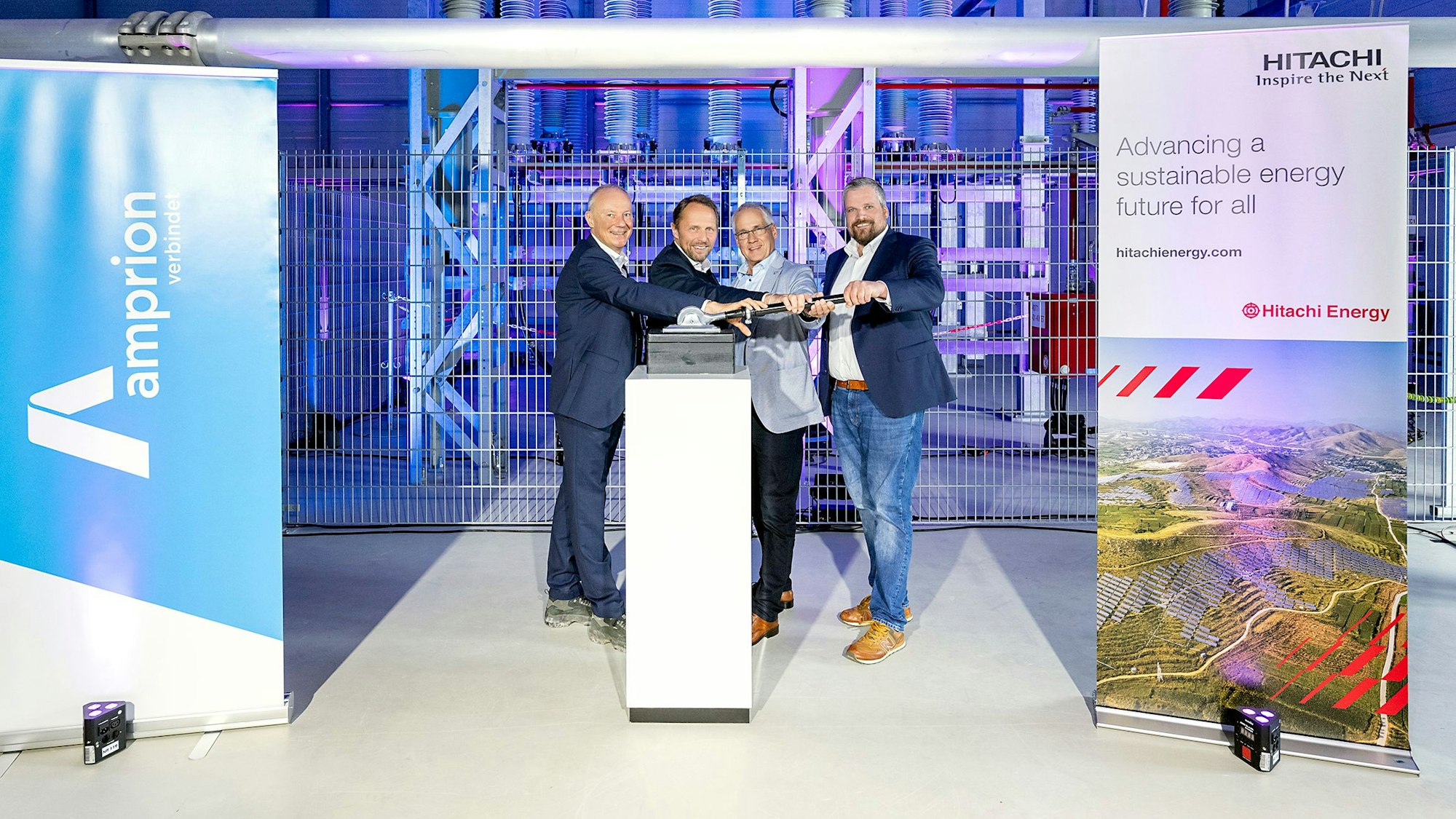 Vier Männer betätigen einen Hebel.