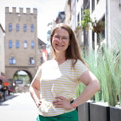 Vera Passy posiert lächelnd vor der Severinstorburg.