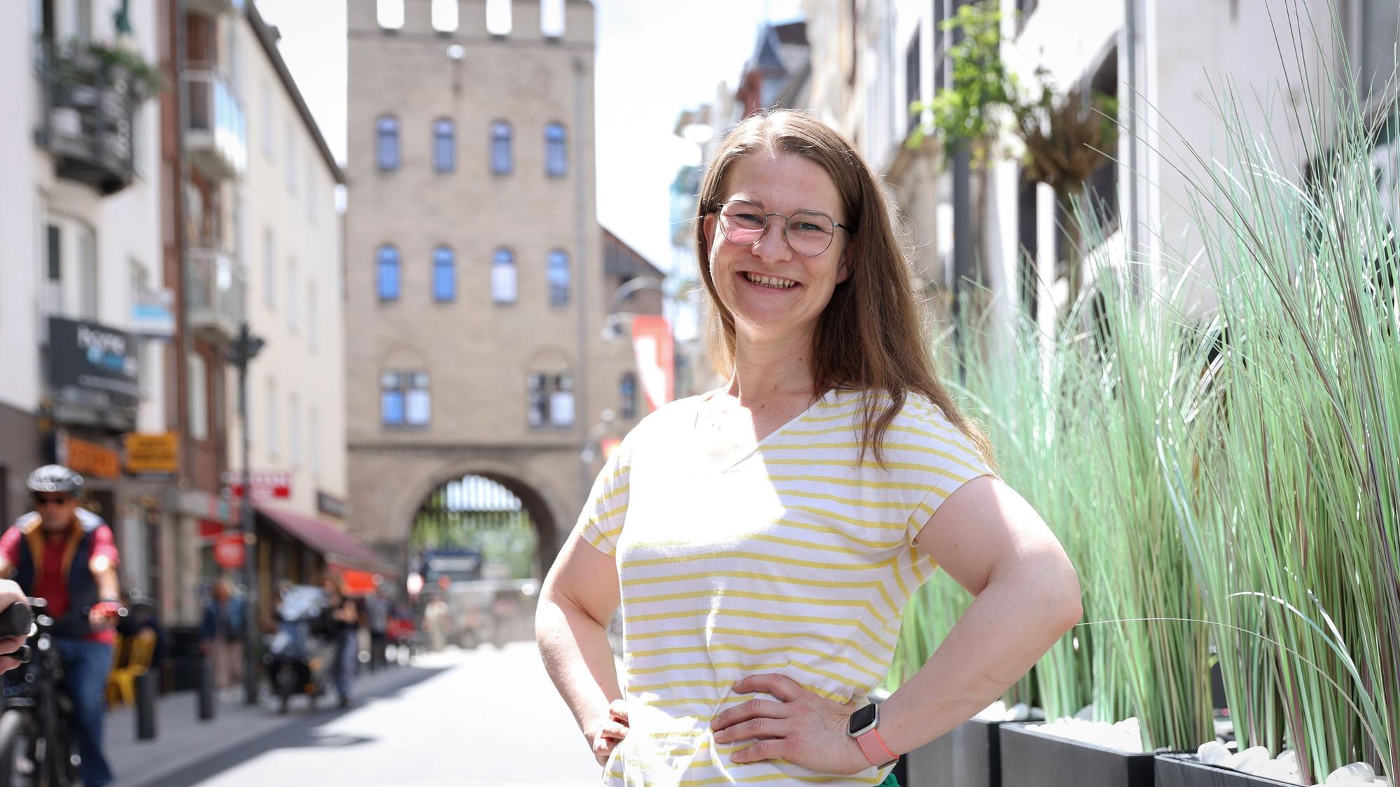 Vera Passy posiert lächelnd vor der Severinstorburg.