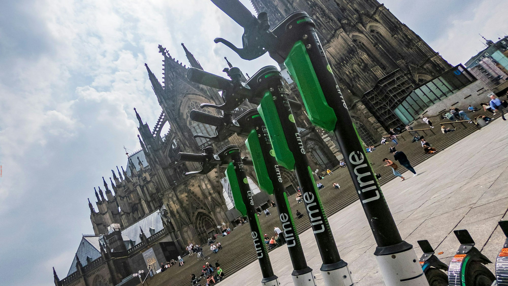 Mehrere E-Scooter des Anbieters „Lime“ stehen auf dem Bahnhofsvorplatz am Kölner Hauptbahnhof vor dem Kölner Dom.