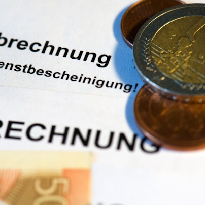 Auf einer Verdienstbescheinigung liegen Euromünzen und Geldscheine.