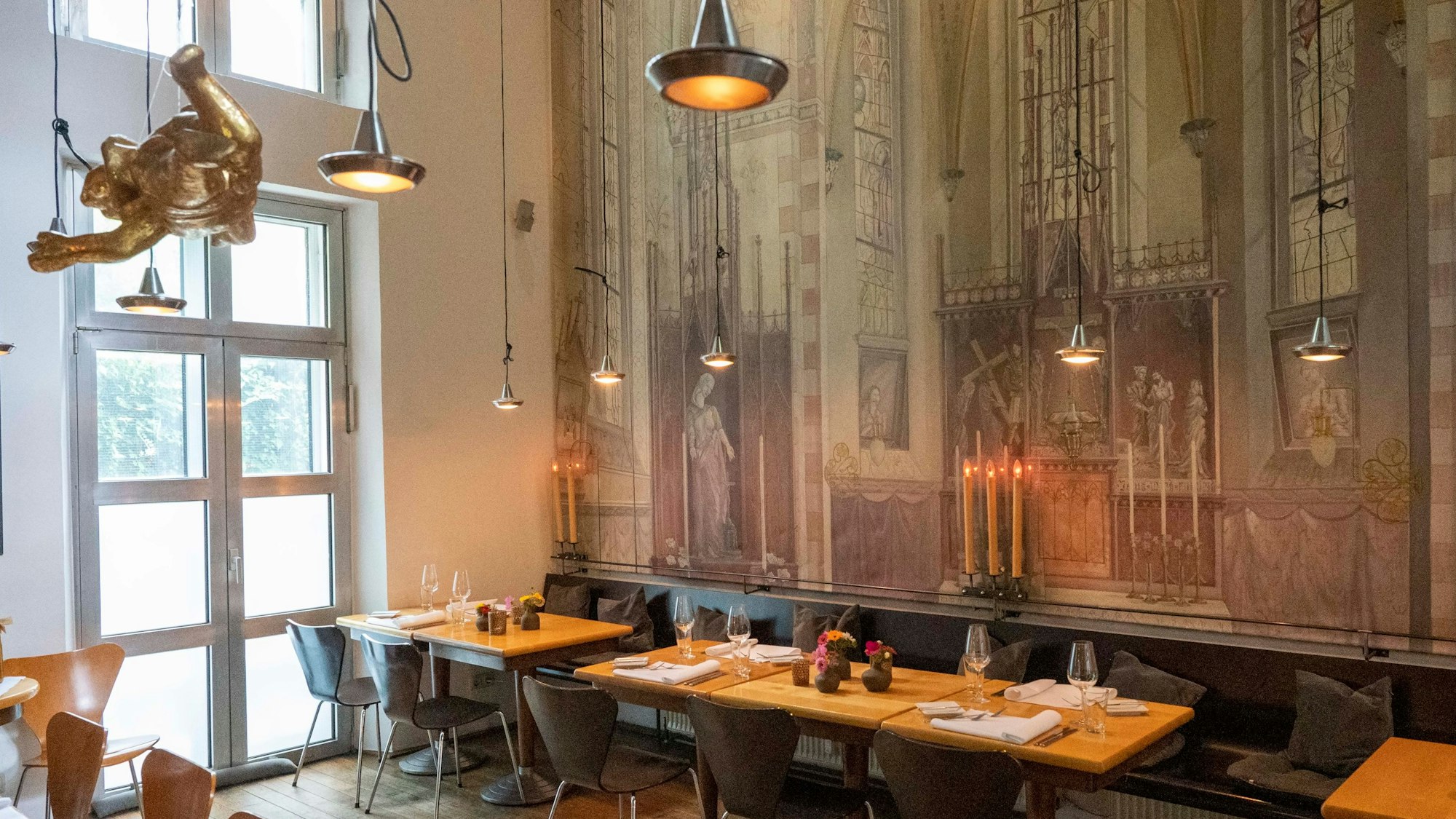 Tische und Stühle stehen vor einer Wand, die wie die Kapelle bemalt ist.