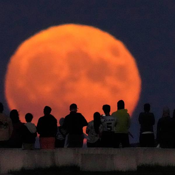 Der Vollmond erhebt sich über dem Lake Michigan, während Zuschauer vom Strand der 31st Street in Chicago aus zusehen.