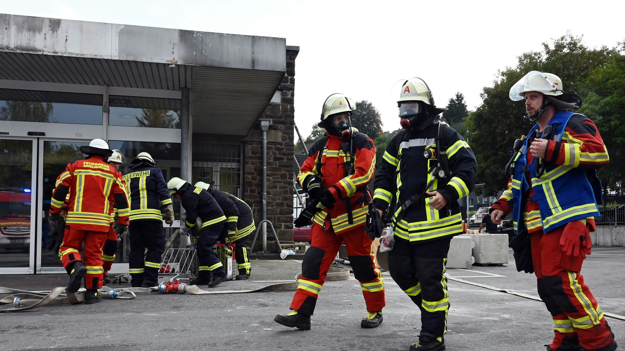 Einsatzkräfte der Feuerwehren von Ründeroth und Osberghausen mit Atemschutz vor dem Eingang eines leerstehenden Supermarkts.