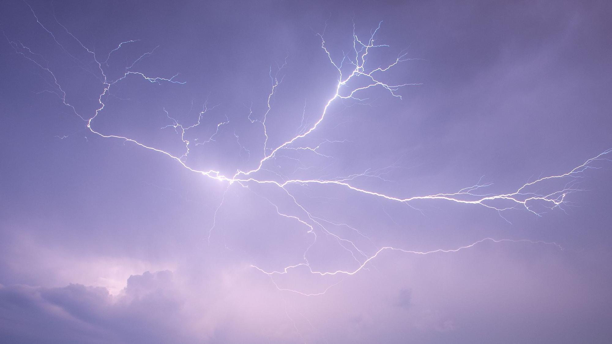 Mehrere Blitze lassen während eines Unwetters den Himmel lila erleuchten.