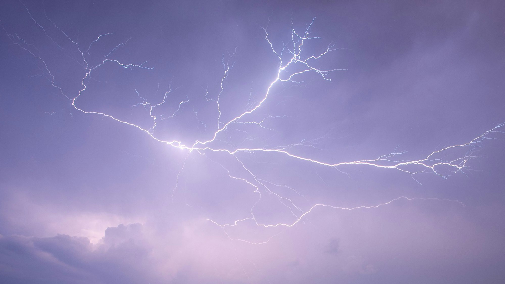 Mehrere Blitze lassen während eines Unwetters den Himmel lila erleuchten.