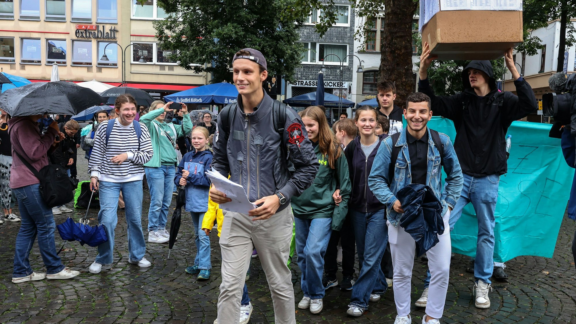 Eine Gruppe von Schülerinnen und Schülern läuft vom Alter Markt zum Historischen Rathaus. Ein Schüler trägt einen Karton.