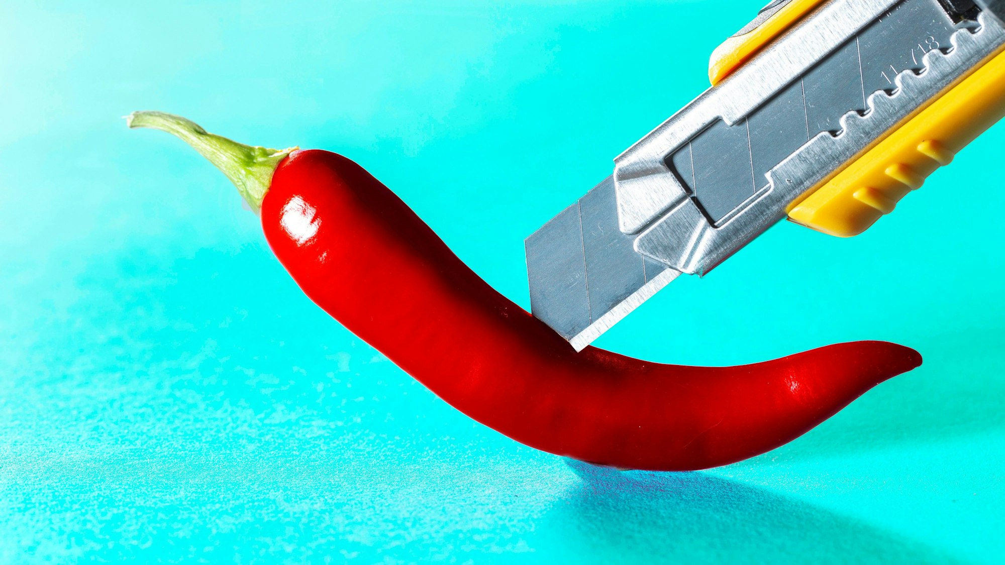 Cuttermesser schneidet in Chili-Schote