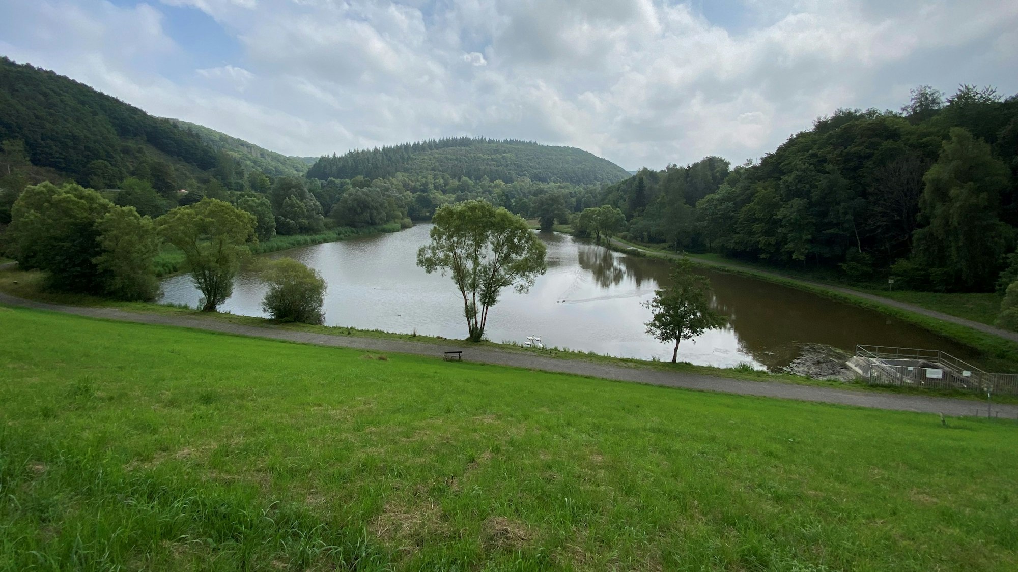 Ein Bild zeigt ein Gewässer umgeben von bewaldeten Hügeln.