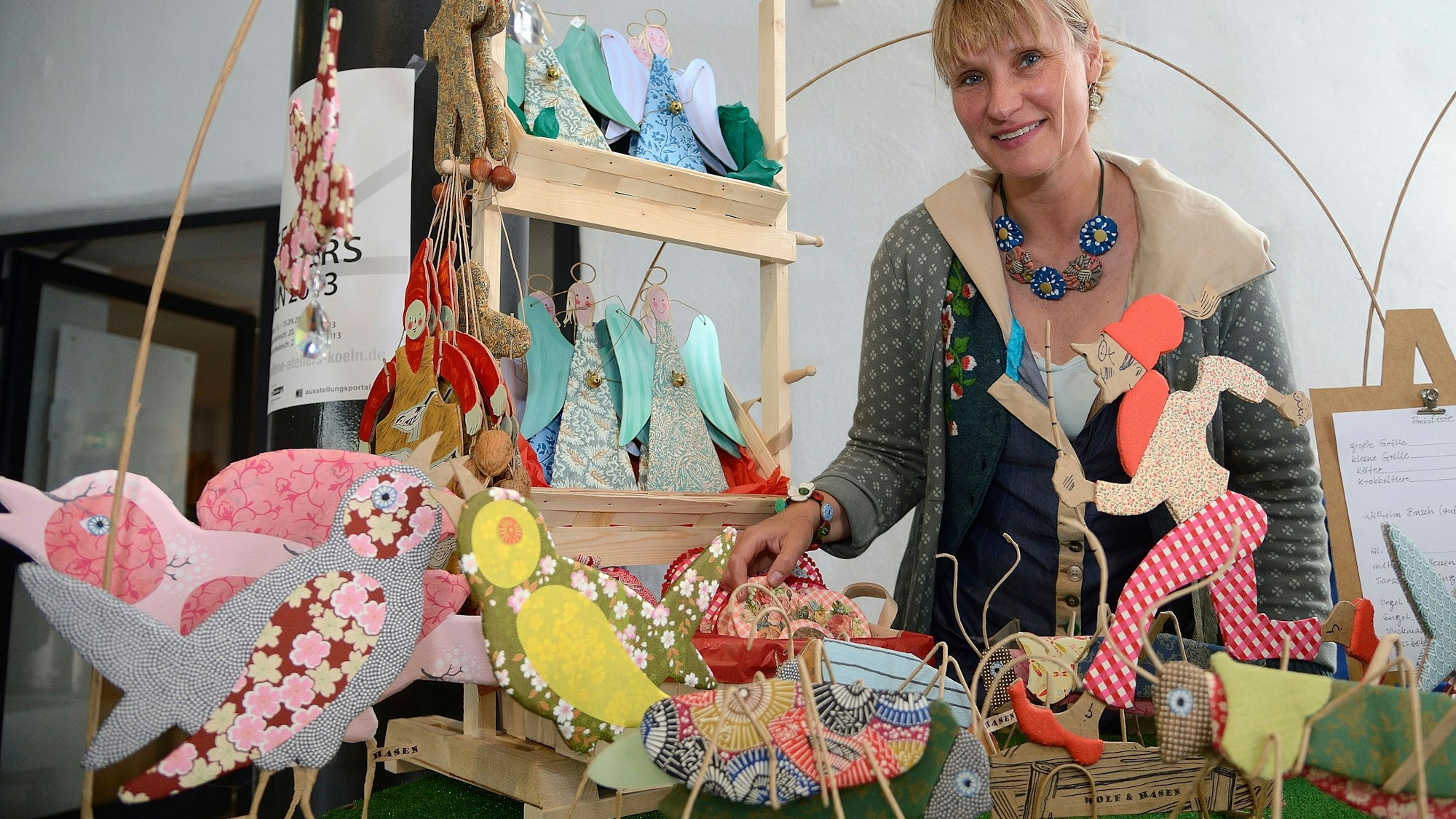 Eine Frau steht hinter Auslagen eines Handarbeitenstands.