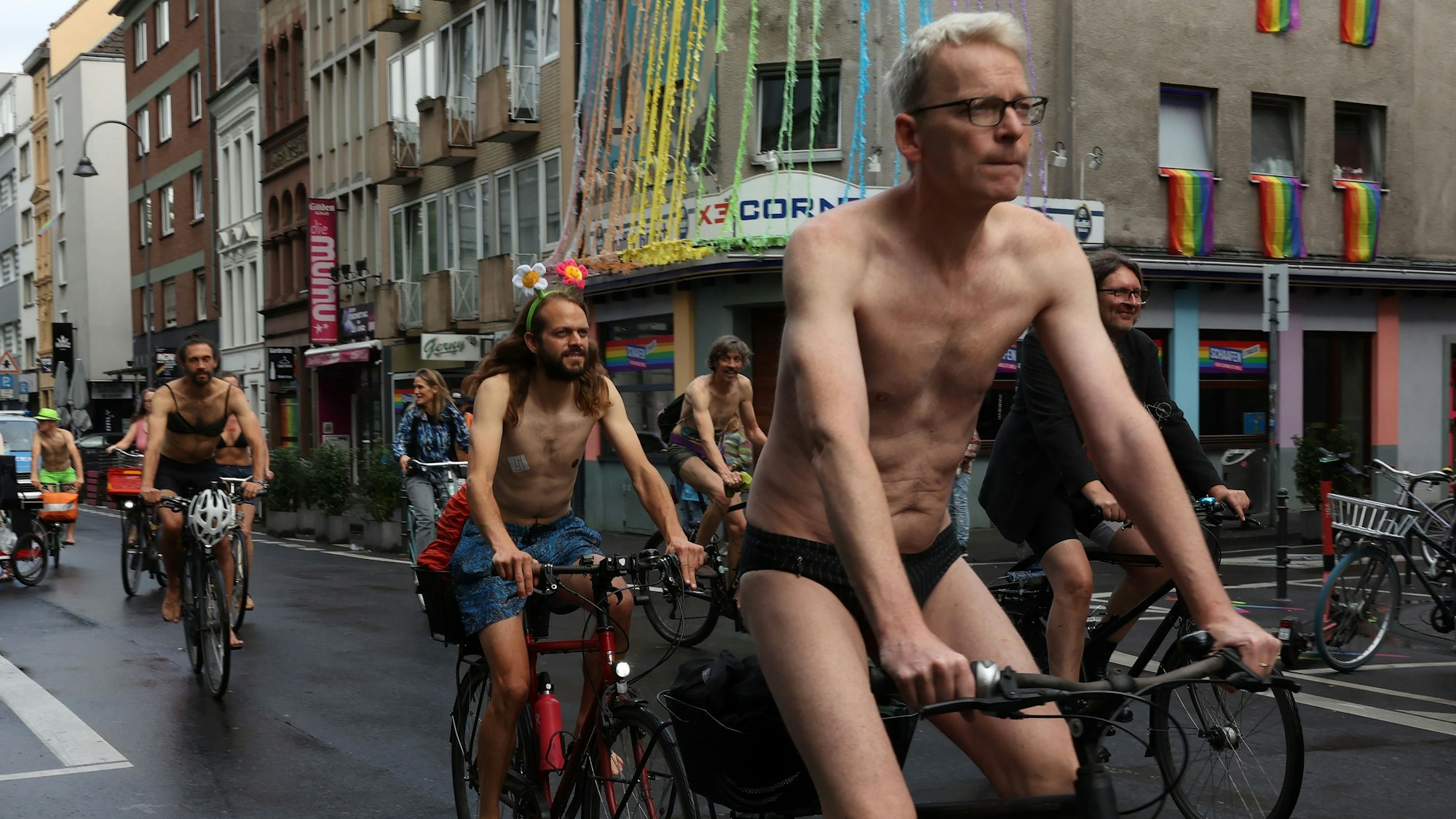 Mehrere Fahrradfahrer fahren spärlich bekleidet durch die Stadt.