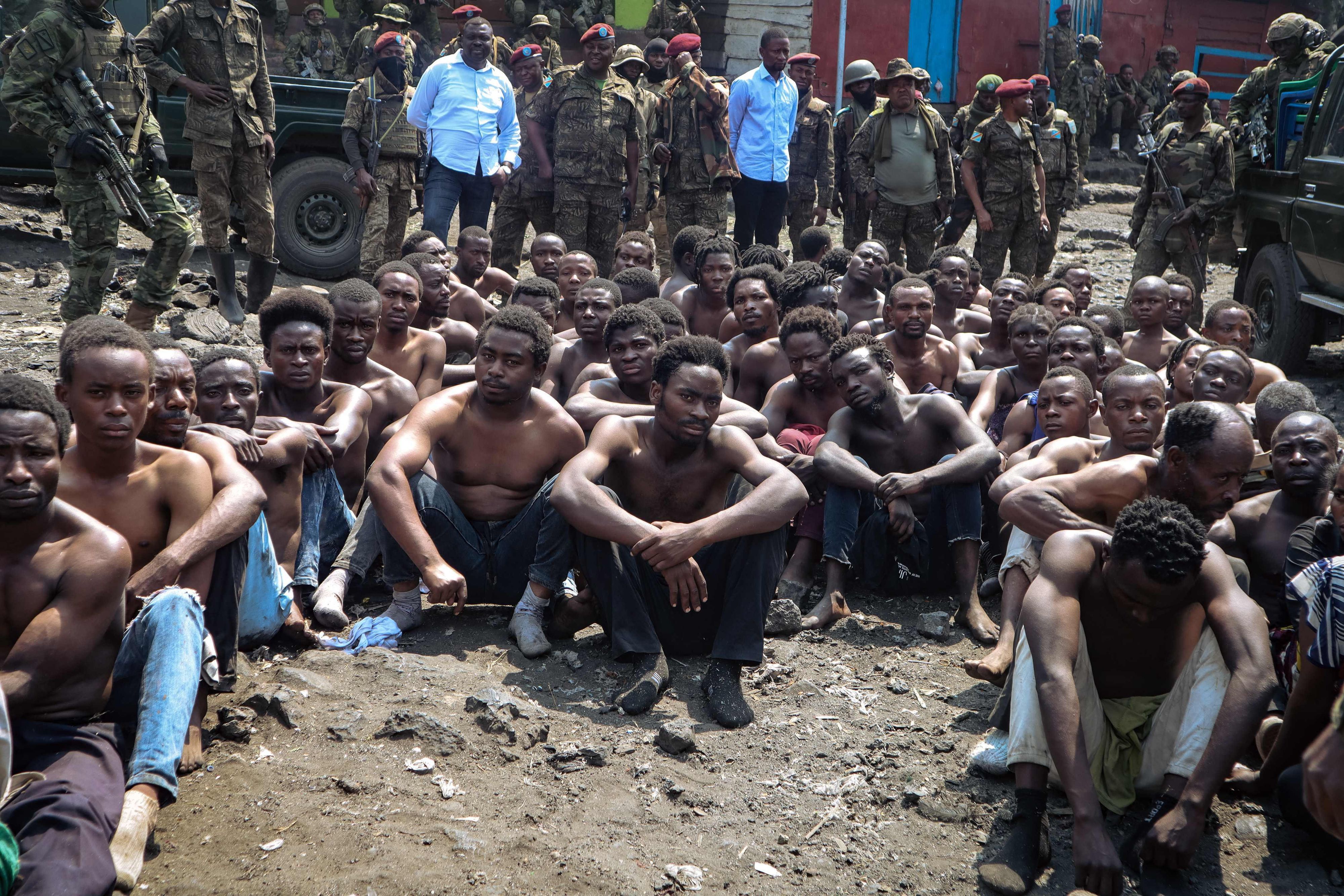 TOPSHOT - People arrested during a military operation to prevent a planned demonstration against the United Nations by a religious sect, sit on the ground and guarded by the army in Goma, eastern Democratic Republic of Congo on August 30, 2023. At least 48 people have been killed and 168 arrested in a crackdown on an anti-UN protest in eastern DR Congo, according to sources and official documentation. On August 30, 2023, Congolese soldiers stopped a religious sect from holding a demonstration against United Nations peacekeepers in the city of Goma. (Photo by AFP)