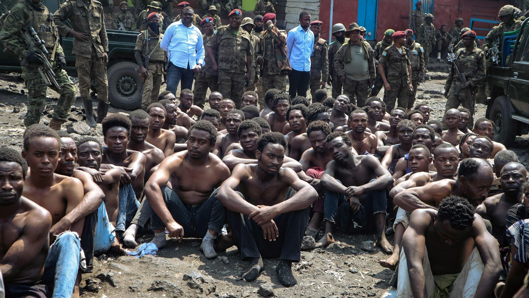 TOPSHOT - People arrested during a military operation to prevent a planned demonstration against the United Nations by a religious sect, sit on the ground and guarded by the army in Goma, eastern Democratic Republic of Congo on August 30, 2023. At least 48 people have been killed and 168 arrested in a crackdown on an anti-UN protest in eastern DR Congo, according to sources and official documentation. On August 30, 2023, Congolese soldiers stopped a religious sect from holding a demonstration against United Nations peacekeepers in the city of Goma. (Photo by AFP)