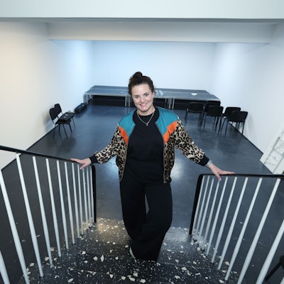 Lene Breuer steht auf der Treppe, hinter ihr die Bühne und vereinzelte Stühle davor.